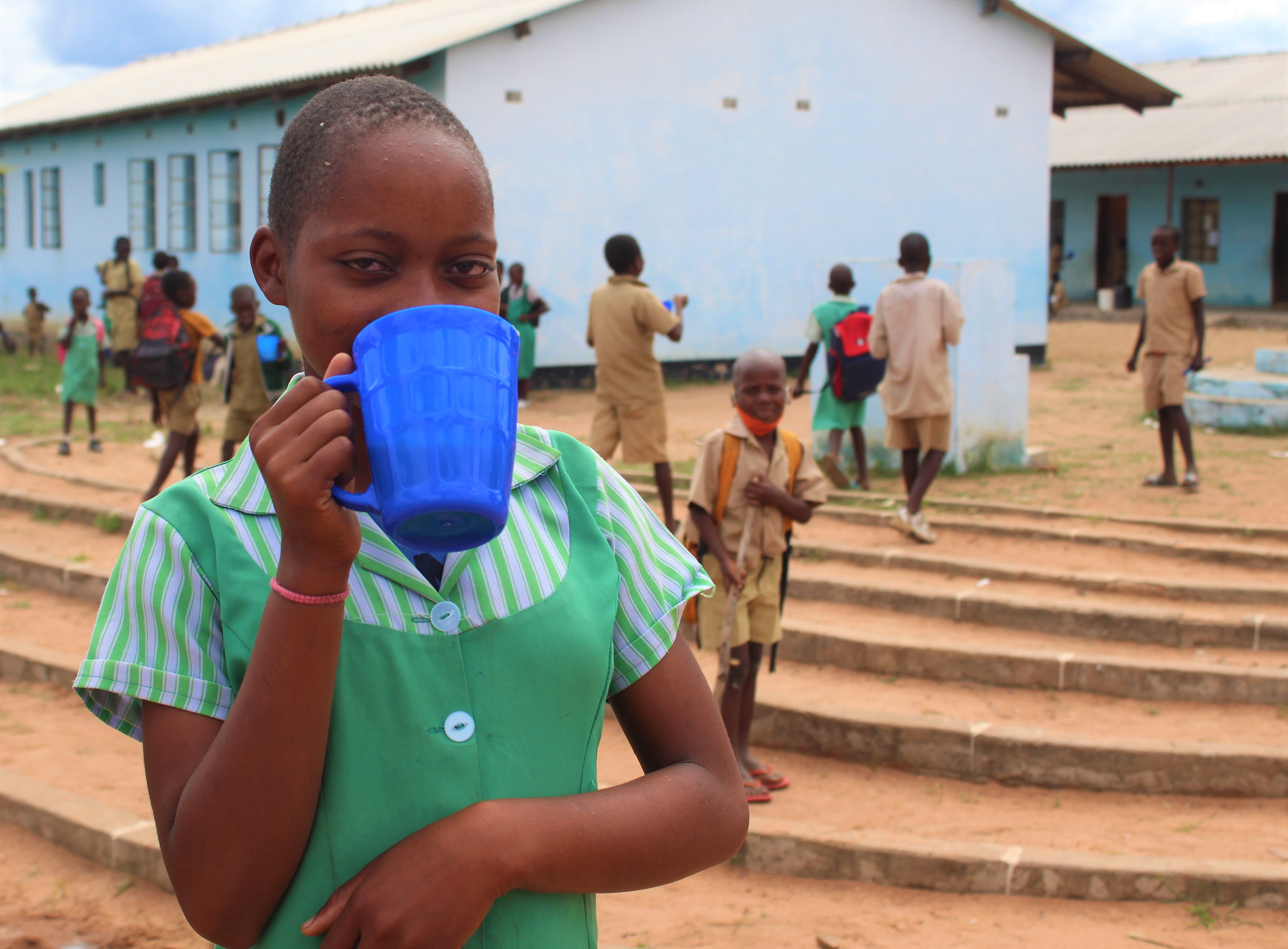 young girl drinking from blue mug