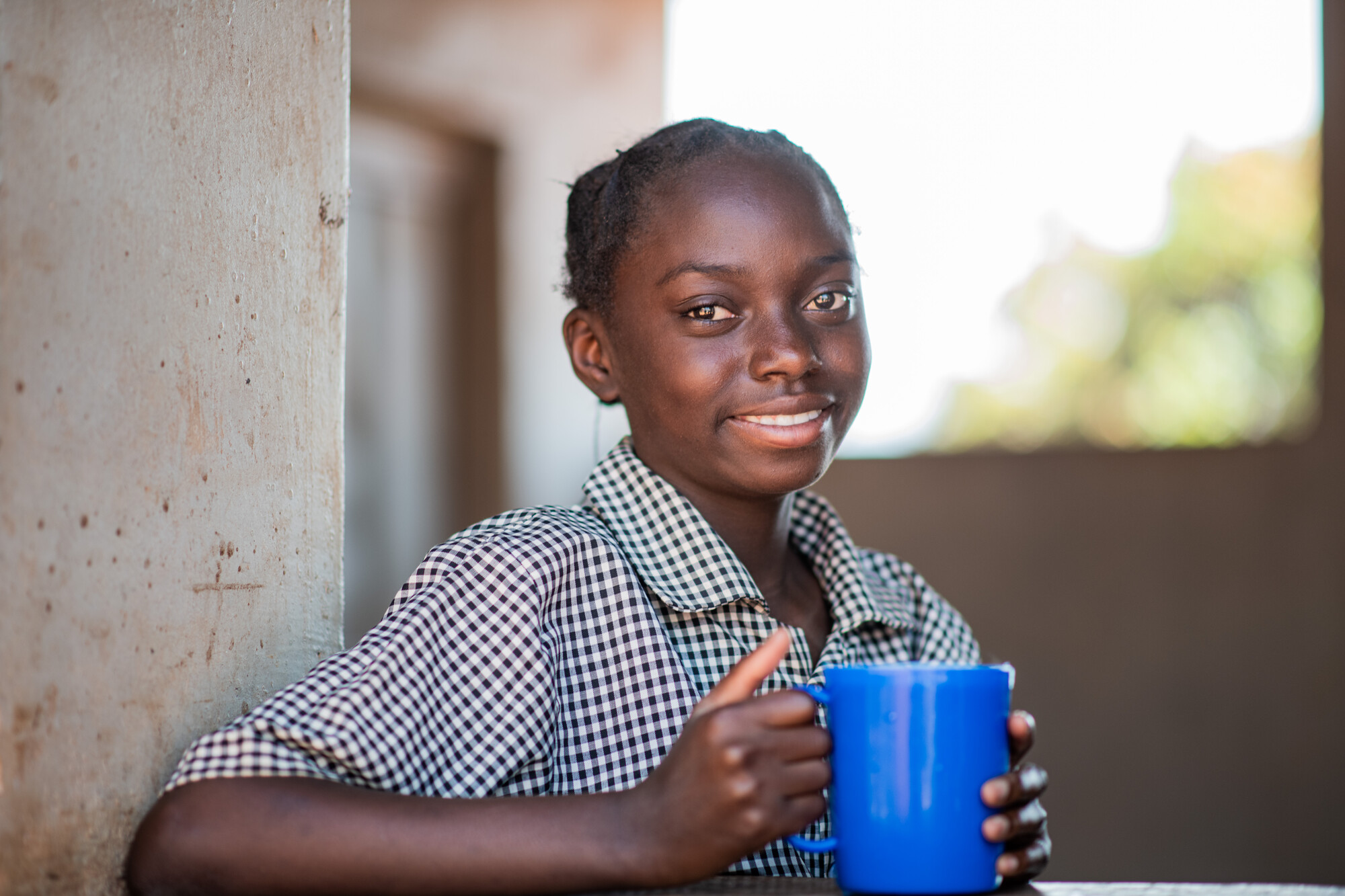 young girl holding a blue mug