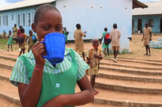 young girl drinking from blue mug 