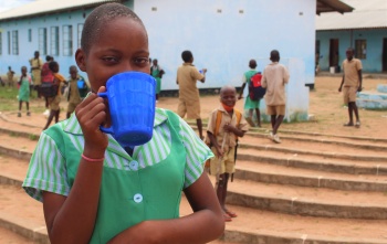young girl drinking from blue mug 