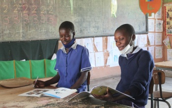 Two children from Zambia learning and reading in their classroom.