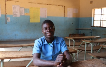young man in class posing for a photo at a desk