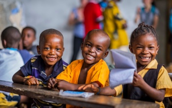 3 children smiling in a classroom