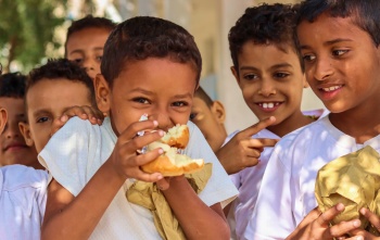 A boy eats in the playground of his school