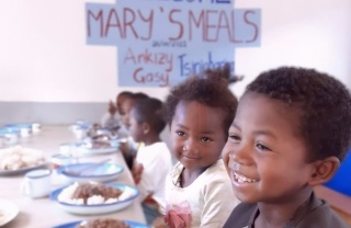 children smiling happily in front of bowls full of food