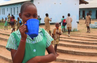 young girl drinking from blue mug 