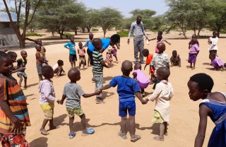 young children outdoors holding hands in a circle formation