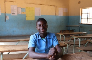 young man in class posing for a photo at a desk