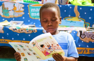 A young boy reads at a book at school.