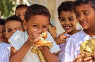 A boy eats in the playground of his school