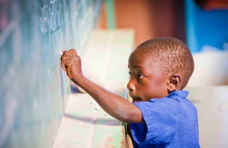 A child writes on a chalkboard