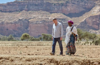 Magnus walks across an Ethiopian landscape alongside a lady from Tigray