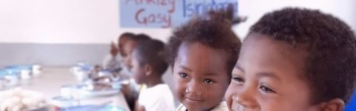 children smiling happily in front of bowls full of food