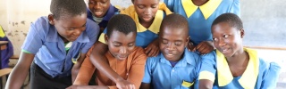 Ulemu with his classmates reading a book. 