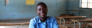 young man in class posing for a photo at a desk