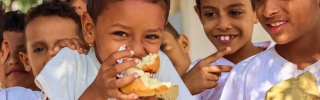 A boy eats in the playground of his school