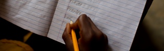 A child writes in their notepad