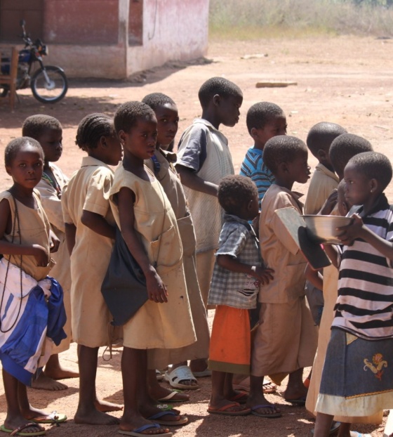 Children in Benin waiting to be served Mary's Meals at school.