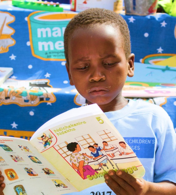 A young boy reads at a book at school.