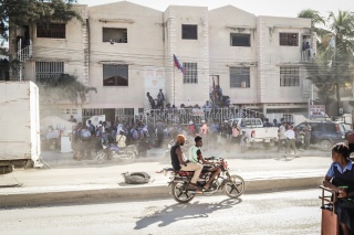 Image of a busy street in Haiti as school children gather outside of school.